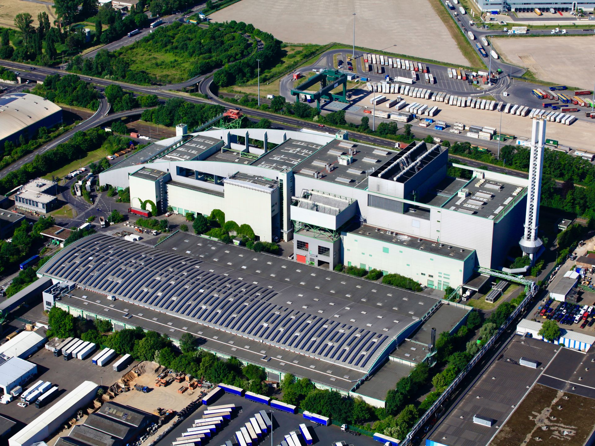 Luftbild zeigt Kompostierungsanlage und Restmüllverbrennungsanlage, im Hintergrund parken viele Lkw eines anderen Unternehmens