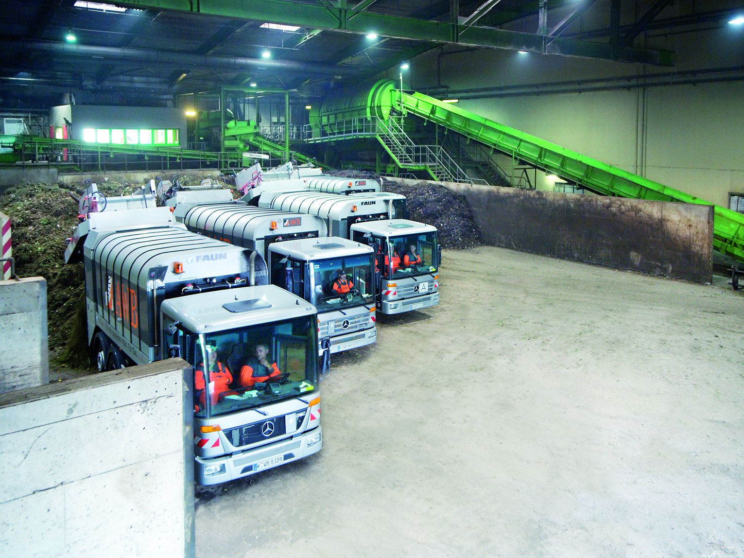 Drei Müllfahrzeuge der AWB Köln liefern in der Halle der Kompostierungsanlage Bioabfälle an. 