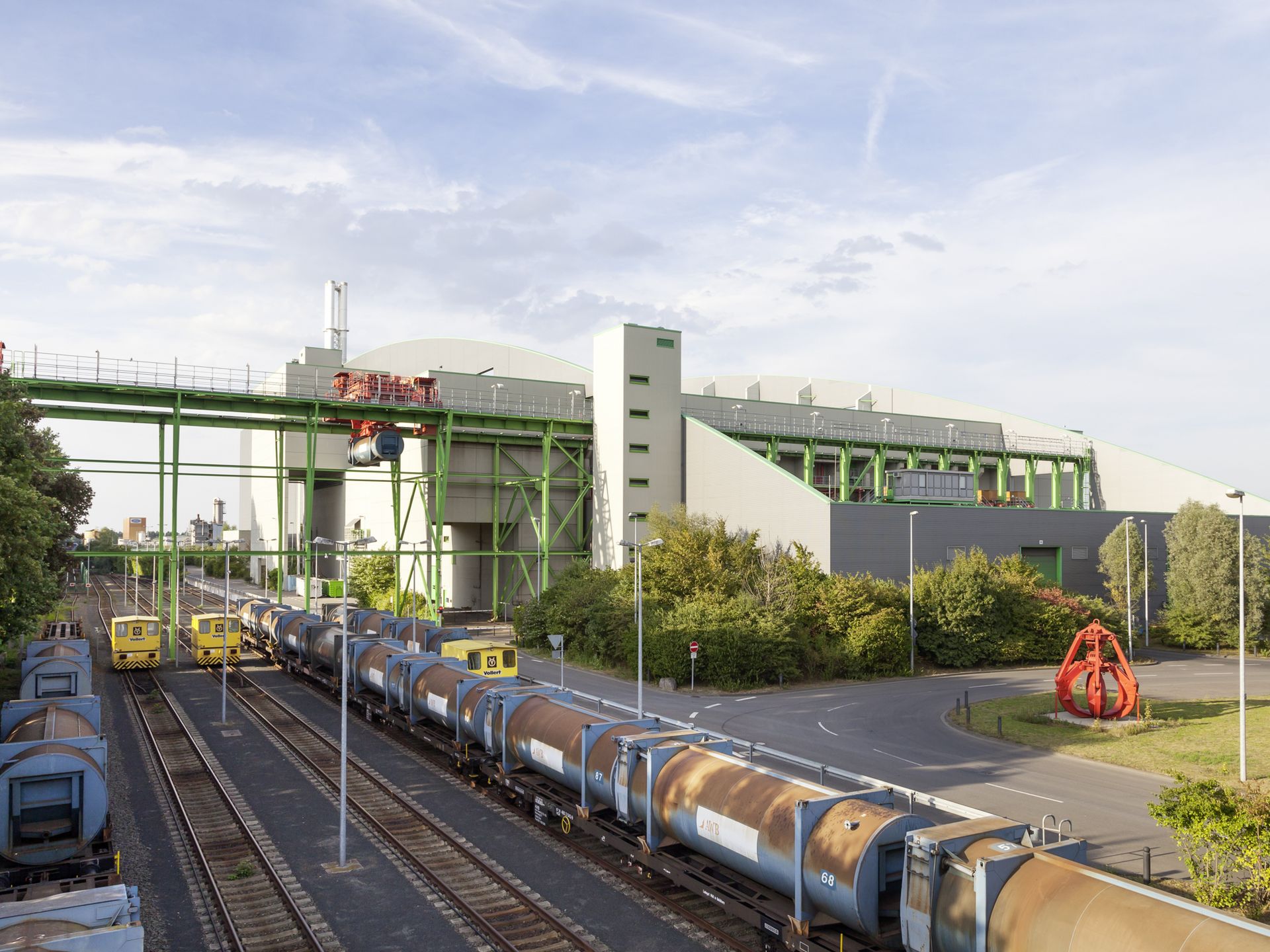 Restmüllverbrennungsanlage mit Station für die Bahnanlieferung des Hausmülls Restmüllverbrennungsanlage Köln mit Zügen, die den Kölner Hausmüll zur Anlage transportieren, am Bildrand ein roter Müllgreifer