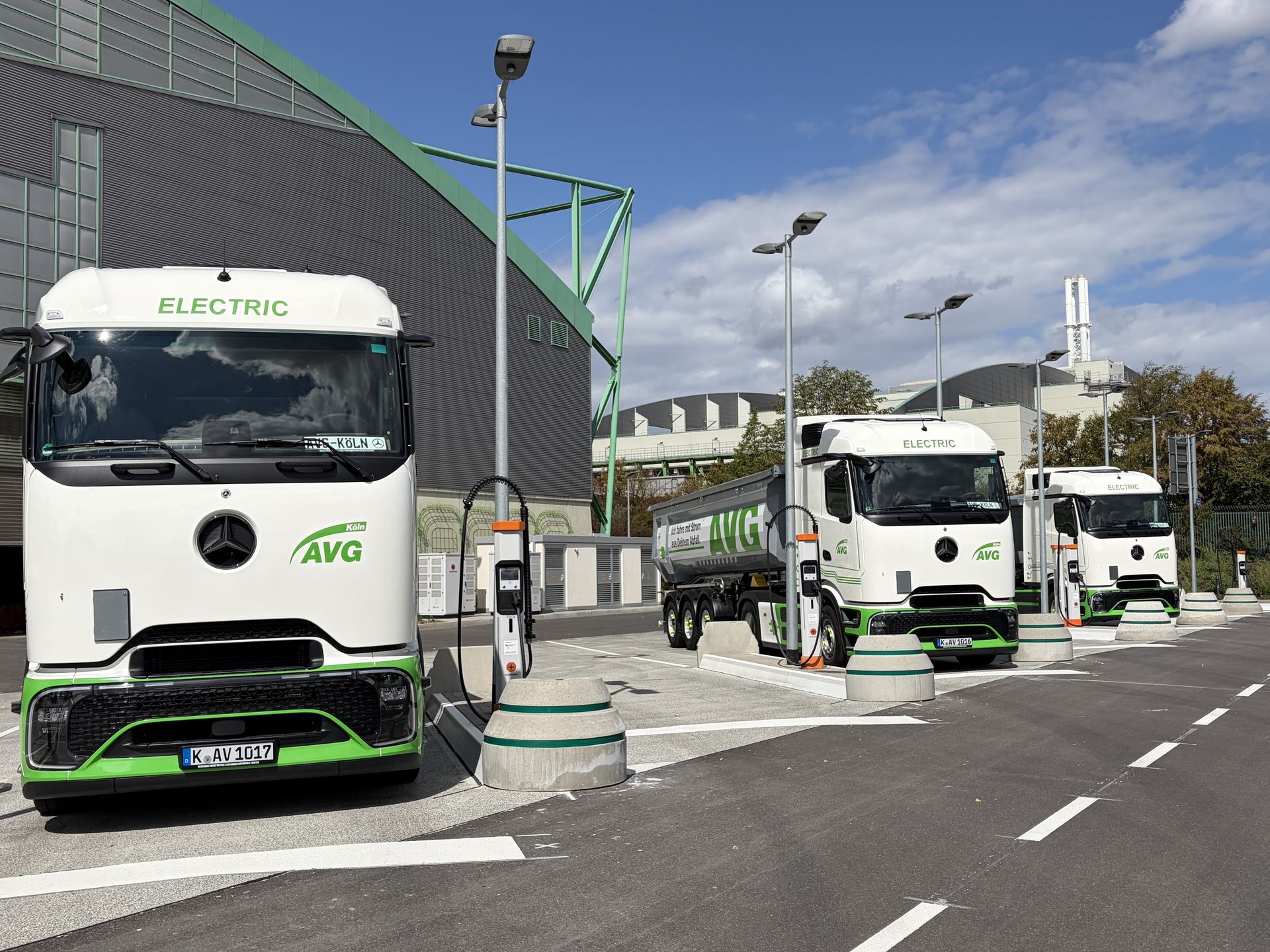 Drei E-Lkw. gebrandet auf AVG Köln, stehen an den Ladesäulen des AVG-E-Ladeparks